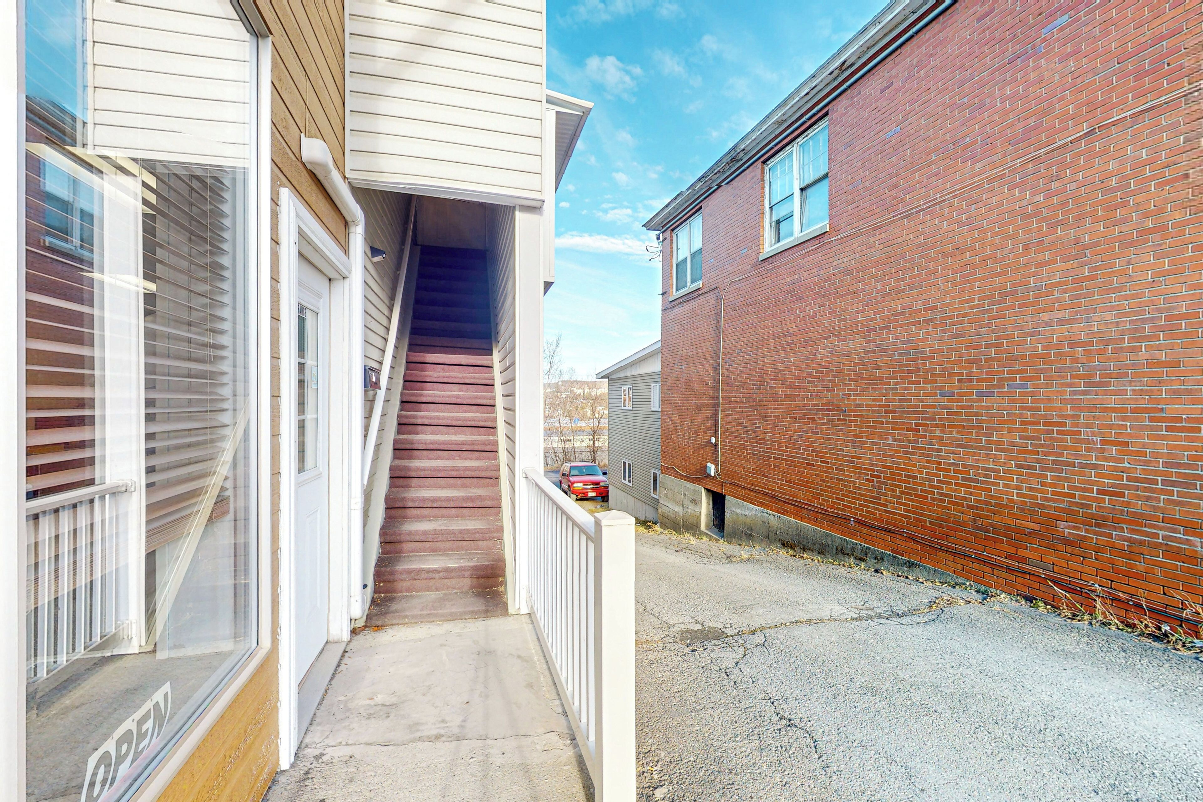 A narrow, enclosed walkway between two buildings, one with a wooden exterior and the other with a brick facade.