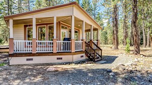 Une cabane avec une véranda, un escalier et un barbecue.