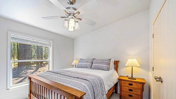 Une chambre à coucher avec un lit, une table de chevet, une lampe et une fenêtre avec des stores.