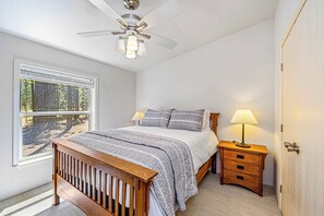 A bedroom with a bed, bedside table, lamp, and a window with blinds. - Dog-friendly 3BR on 200 Acres w/ River Access (Blairsden-Graeagle)