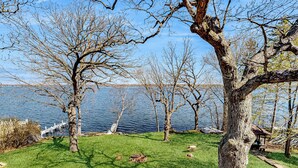 A lakeside property with a grassy lawn, several trees, and a wooden deck. - 6BR Lakefront Estate w/ Private Piers & Patios (Ripon)