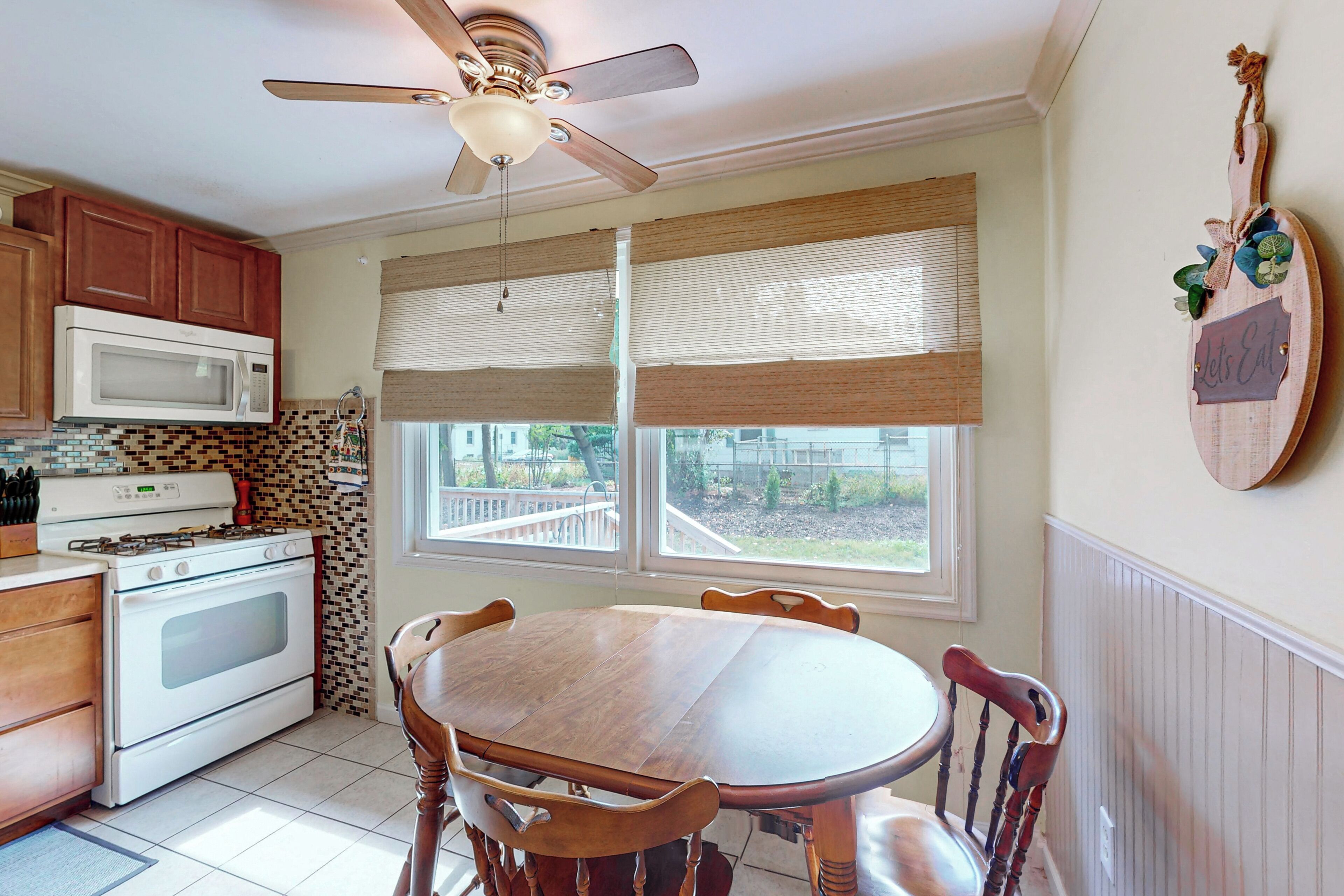 A kitchen with wooden cabinets, a microwave, stove, and a dining table with chairs.