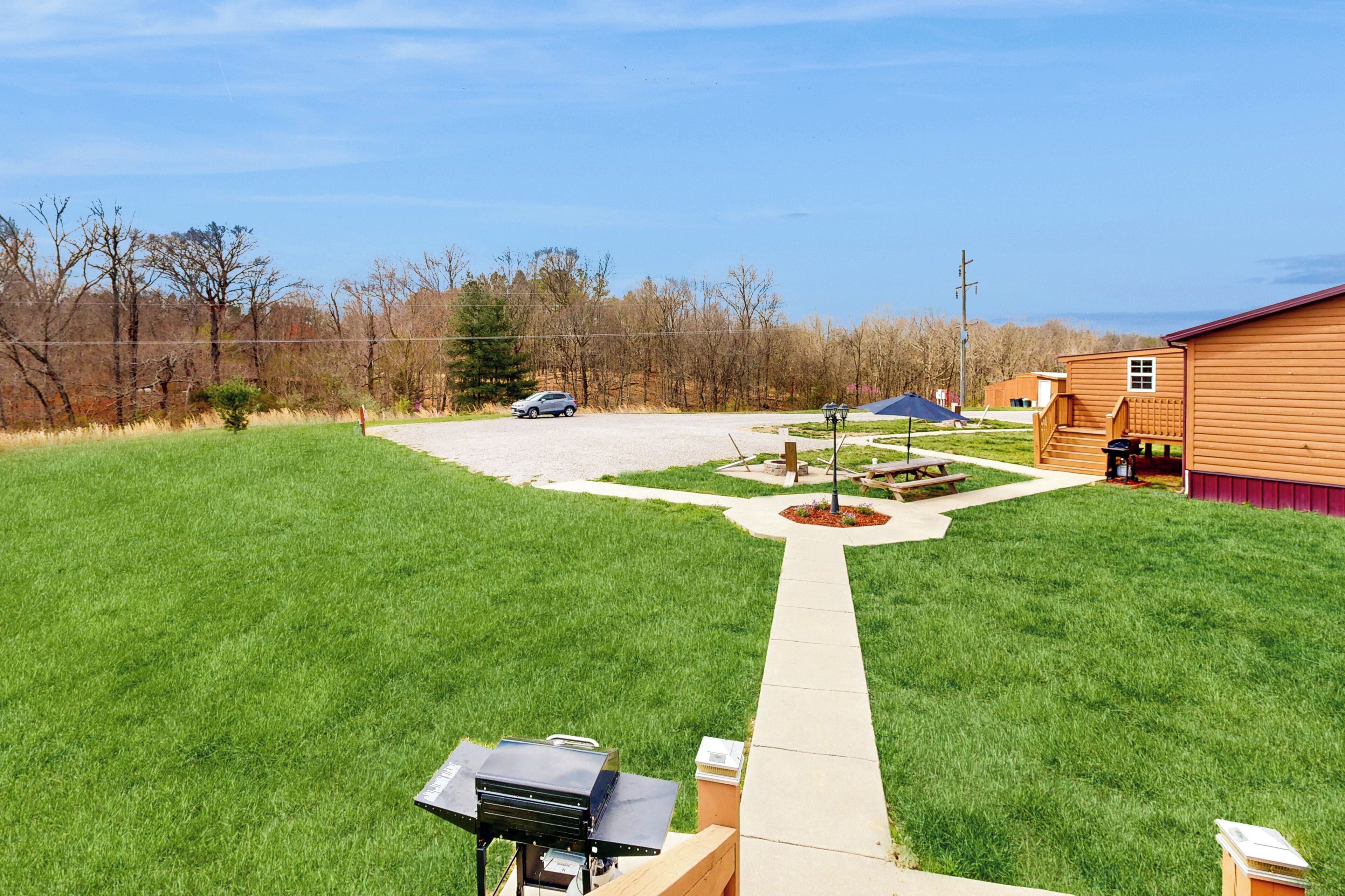 Un patio trasero con una parrilla, una mesa de picnic y una terraza de madera que conduce a una casa.