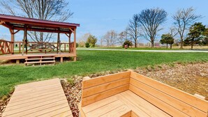 A wooden deck with a picnic table and a covered seating area in a park.