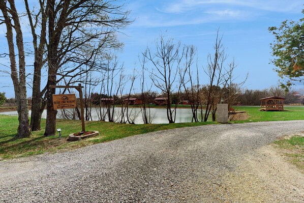 A gravel path leading to a lake with a sign for Blue Line Resort. - Blue Line Resort - All 3 Cabins! (Murphysboro)