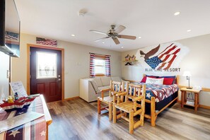 A room with a bed, a wooden chair, a small table, a ceiling fan, and an American flag decoration. - Blue Line Resort - All 3 Cabins! (Murphysboro)