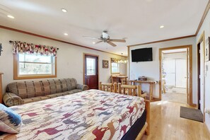A bedroom with a large bed, a ceiling fan, a wooden desk, and a television on the wall. - Blue Line Resort - All 3 Cabins! (Murphysboro)