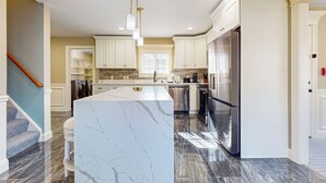A modern kitchen with marble countertops, stainless steel appliances, and pendant lighting. - Steps to Holyoke Medical Center! Remote-work Hub (Holyoke)