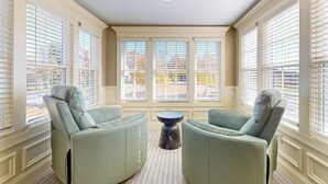 A room with two green armchairs facing a central table, large windows with blinds, and a ceiling light fixture. - Steps to Holyoke Medical Center! Remote-work Hub (Holyoke)