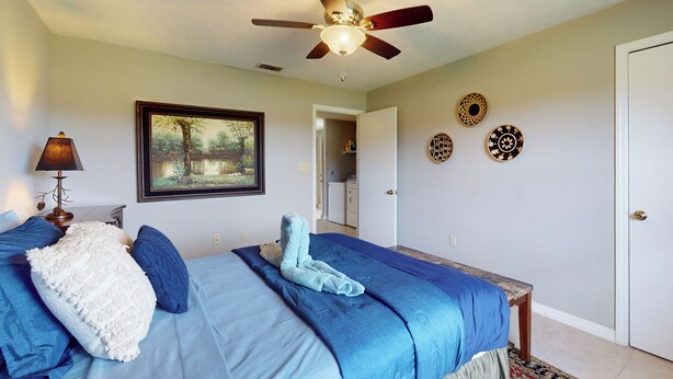 Ein Schlafzimmer mit einem Bett, einem Deckenventilator, einem gerahmten Bild und dekorativen Tellern an der Wand.