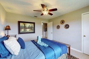 Een slaapkamer met een bed, een plafondventilator, een ingelijst schilderij en decoratieve borden aan de muur.