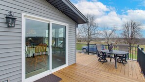 A deck with a table and chairs, a sliding glass door, and a lantern. - Newly Updated Countryside Home in South Gorin! (South Gorin)