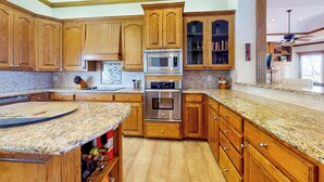 A kitchen with wooden cabinets, granite countertops, stainless steel appliances, and a built-in wine rack. - Lakefront Estate: Stunning Views, Deck, Bar & Dock (Bridgeport)