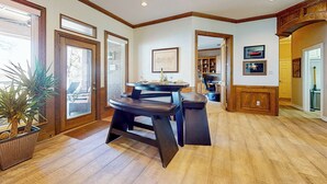A spacious room with a wooden floor, a dining table with chairs, and a large window with a view. - Lakefront Estate: Stunning Views, Deck, Bar & Dock (Bridgeport)