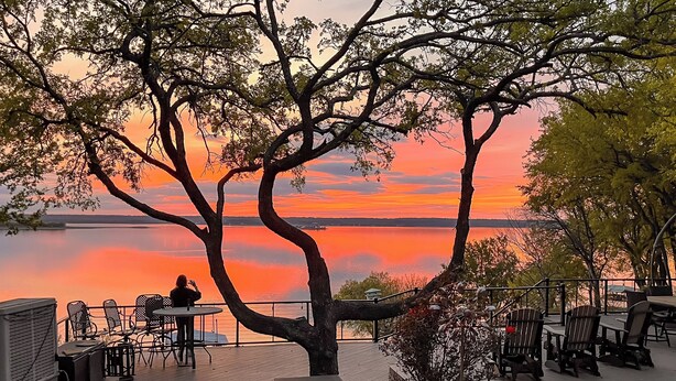A lakeside patio with outdoor seating and a view of the sunset. - Lakefront Estate: Stunning Views, Deck, Bar & Dock (Bridgeport)