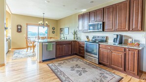 A modern kitchen with wooden cabinets, stainless steel appliances, and a large island. - Breathtaking Mountain & Lake Views! (Dayton)