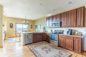 A modern kitchen with wooden cabinets, stainless steel appliances, and a large island. - Breathtaking Mountain & Lake Views! (Dayton)