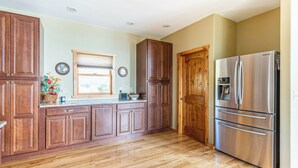 A kitchen with wooden cabinets, a stainless steel refrigerator, and a window with blinds. - Breathtaking Mountain & Lake Views! (Dayton)