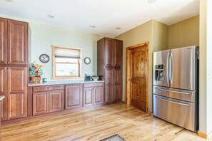 A kitchen with wooden cabinets, a stainless steel refrigerator, and a window with blinds. - Breathtaking Mountain & Lake Views! (Dayton)