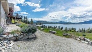 A house with a balcony overlooking a lake, surrounded by greenery and mountains. - Breathtaking Mountain & Lake Views! (Dayton)