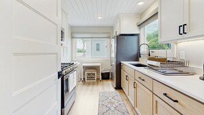 A modern kitchen with white cabinetry, a black refrigerator, a built-in oven, and a window providing natural light. - 3 BR Lakefront House w/ Private Dock (Lodi)