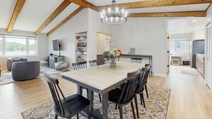 A spacious dining area with a wooden ceiling, a chandelier, and a large table surrounded by chairs. - 3 BR Lakefront House w/ Private Dock (Lodi)