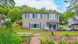 A two-story house with a front deck, a small pond, and a garden area. - 3 BR Lakefront House w/ Private Dock (Lodi)