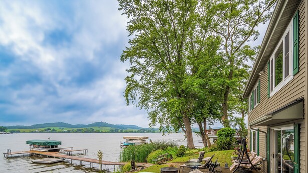 A lakeside property with a dock, boats, and outdoor seating. - 3 BR Lakefront House w/ Private Dock (Lodi)