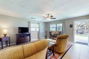 A living room with a sofa, a television, a ceiling fan, and a dining area with chairs and a table. - 1 BR Guesthouse w/ Full Kitchen & Lake View (Micanopy)