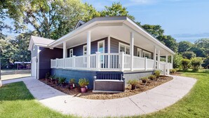 Ein zweistöckiges Haus mit überdachter Veranda, einem kleinen Vorgarten mit Blumentöpfen und einer Auffahrt.