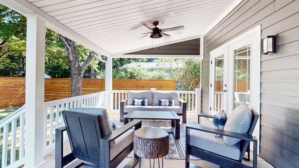 Eine überdachte Terrasse mit Deckenventilator, einer Sofagruppe und zwei Sesseln.