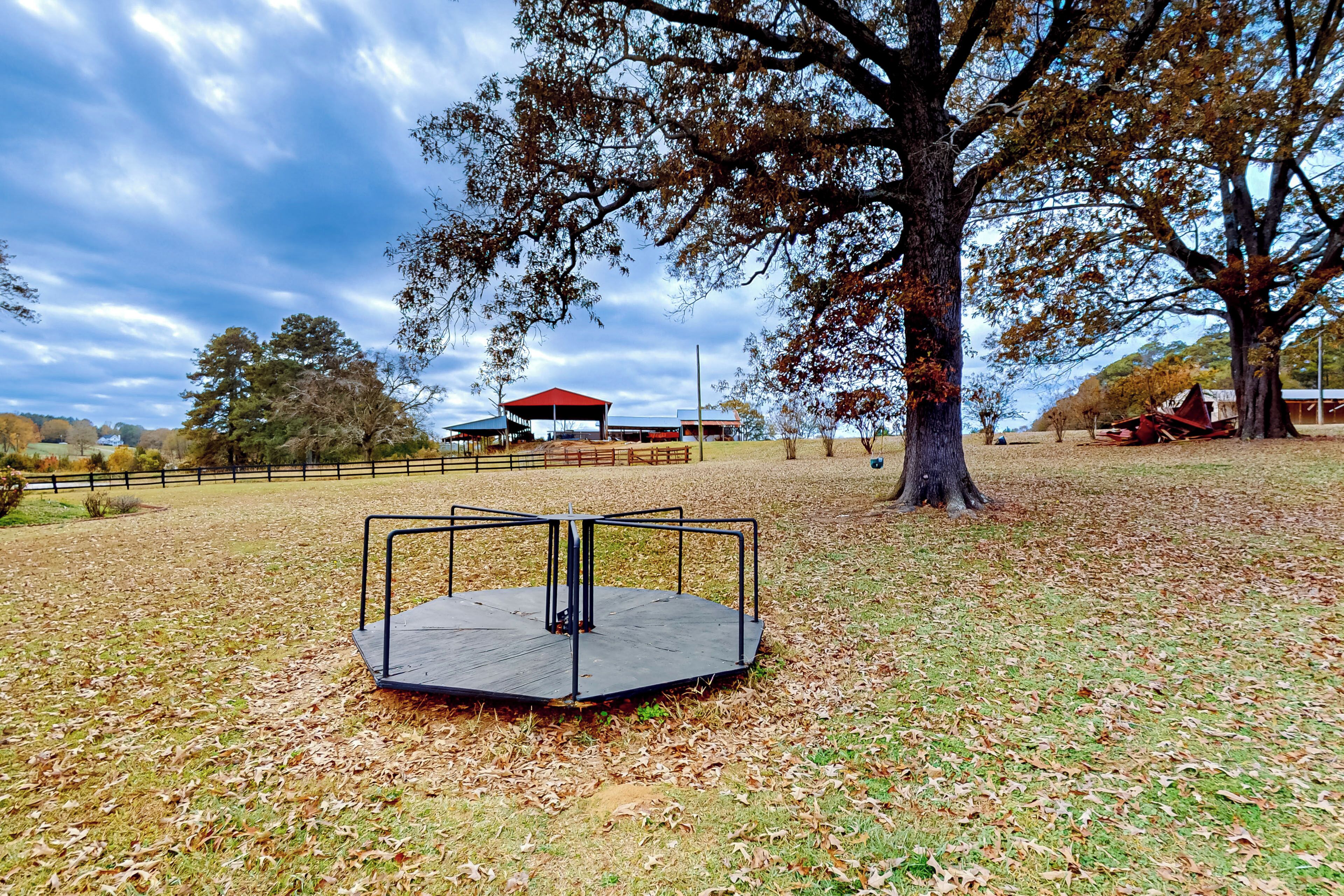 A park with a metal structure, trees, and a distant building.