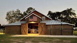 A wooden barn with an open entrance, an American flag, and a metal roof. - Dairy Cottage w/ Scenic Views, Outdoor Grilling (Tylertown)