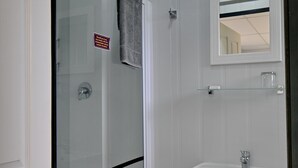 A bathroom with a glass shower enclosure, a white sink, and a mirror above the sink. - SleepOver Colesberg (Colesberg)