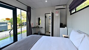 A hotel room with a large bed, a desk, a chair, a small table, and a window with curtains. - SleepOver Colesberg (Colesberg)