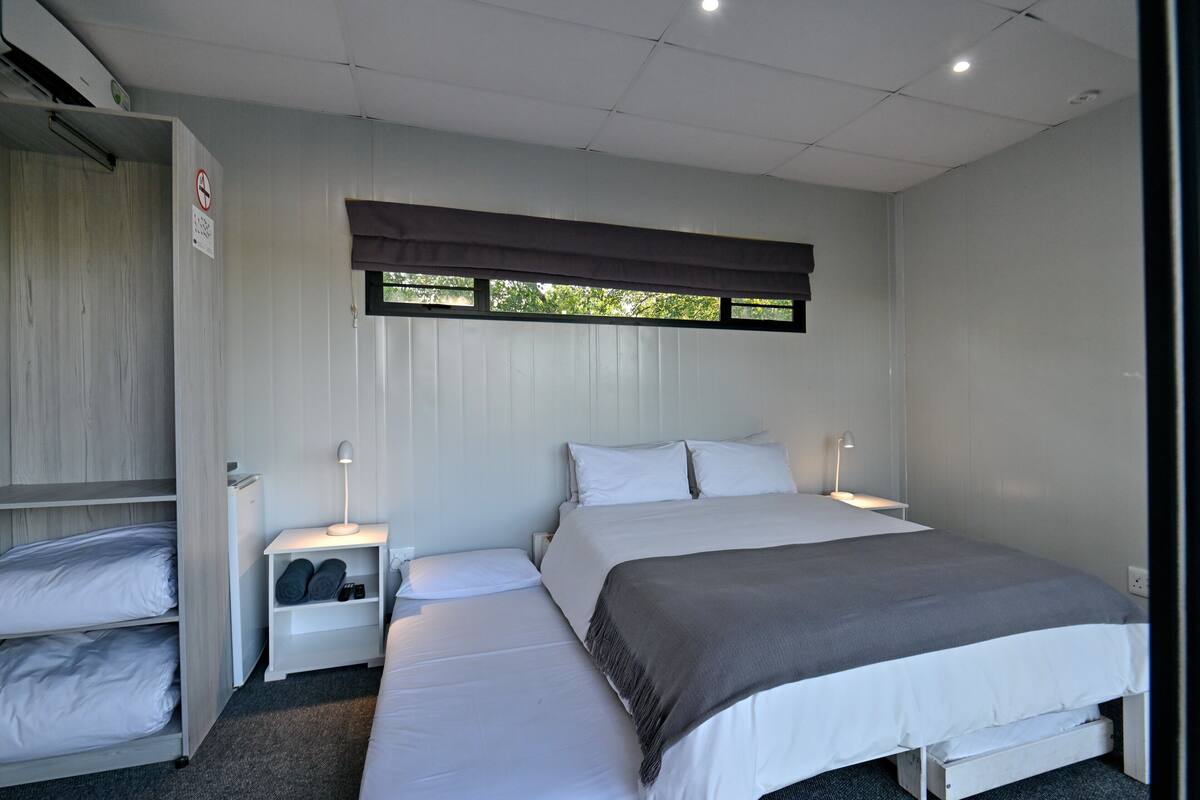 A bedroom with a bed, nightstands, a wardrobe, and a window with blinds.