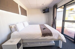 Una habitación de hotel moderna con una cama, un televisor montado en la pared y un ventanal con vistas.