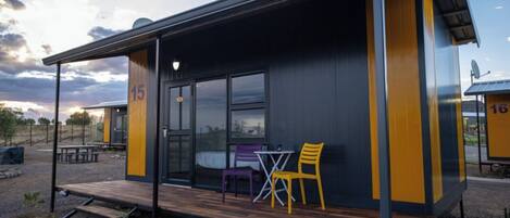 A modern building with a deck, numbered 15 and 16, featuring a glass door and a small table with chairs.