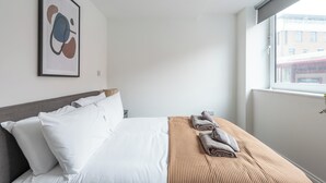 Une chambre d’hôtel avec un lit, des oreillers, une couverture et une œuvre d’art encadrée au mur.