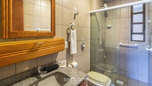 A bathroom with a wooden vanity, a sink, a toilet, and a glass-enclosed shower. - Apart w/ BBC 400 m From the Beach Err0104 (Itapema)