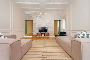 Uma sala de estar moderna com um sofá, uma televisão e um tapete estampado.