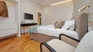 A modern bedroom with a bed, bedside table, TV, and a wardrobe. - Luxury home near Piazza Venezia (Roma)