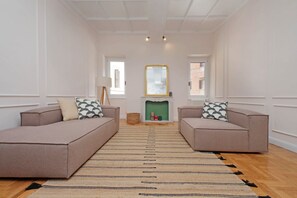 Ein Wohnzimmer mit zwei Sofas, einem Kamin, einem Spiegel und Blick ins Freie.