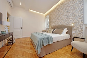 Een slaapkamer met een bed, een bureau, een stoel en een behang met patroon.