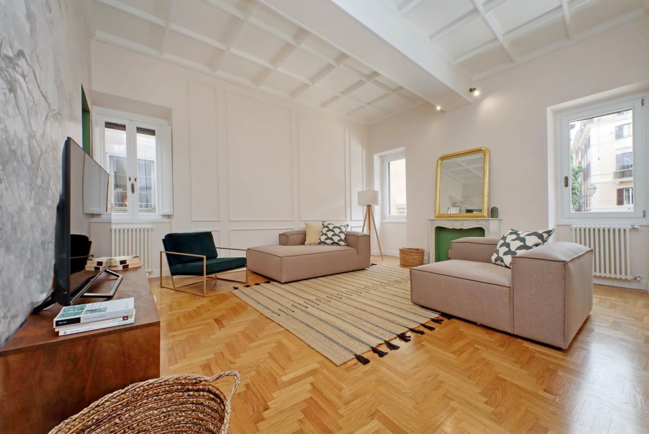Un salon spacieux doté d’un parquet, de deux canapés, d’une table basse, d’un téléviseur et d’un grand miroir.