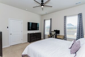 A bedroom with a bed, a ceiling fan, a TV, a dresser, and two windows with patterned curtains. - 4 bed, 3 bath Single Family Home in Millville by the Sea: Community Pool, Fitness Center, Club house, Kayaking, Beach Shuttle, Free WIFI (Frankford)