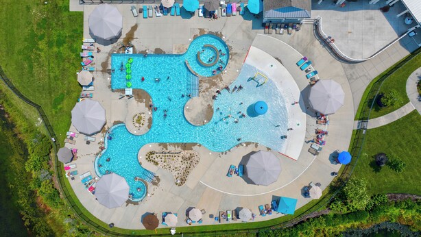 An aerial view of a swimming pool complex with multiple pools, sun loungers, and umbrellas. - 4 bed, 3 bath Single Family Home in Millville by the Sea: Community Pool, Fitness Center, Club house, Kayaking, Beach Shuttle, Free WIFI (Frankford)