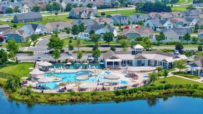 A residential area with a large swimming pool surrounded by houses and a small dock by a lake. - 4 bed, 3 bath Single Family Home in Millville by the Sea: Community Pool, Fitness Center, Club house, Kayaking, Beach Shuttle, Free WIFI (Frankford)
