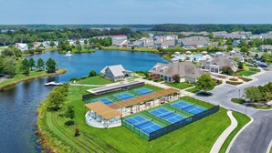A residential area with a tennis court facility, a lake, and houses in the background. - 4 bed, 3 bath Single Family Home in Millville by the Sea: Community Pool, Fitness Center, Club house, Kayaking, Beach Shuttle, Free WIFI (Frankford)