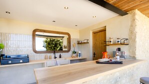 Una cocina moderna con encimera de madera, pared de piedra y ventana con vistas a la vegetación.